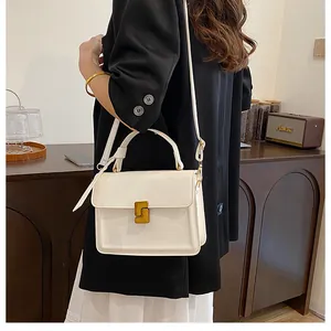 Detail of white rectangle handbag with vintage gold S-shaped lock and adjustable strap