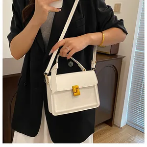 Minimalist white leather crossbody square bag with gold hardware worn by a model