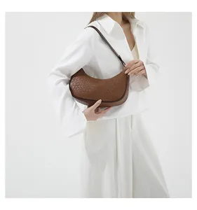 Detailed view of dark brown woven texture on a minimalist crescent crossbody dumpling bag