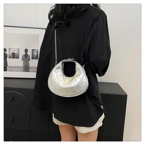 Détail d'un sac demi-lune argenté matelassé avec bandoulière chaîne sur un modèle