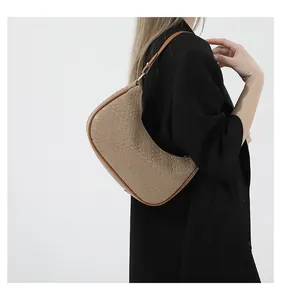 Close-up of khaki woven crescent bag with leather strap on model in black blazer