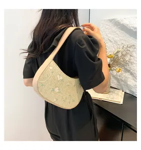 Detailed close-up of green straw shoulder bag with floral embroidery and PU strap
