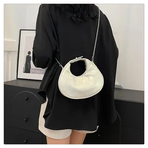 Détail du sac bandoulière blanc matelassé avec chaîne argentée porté par un mannequin
