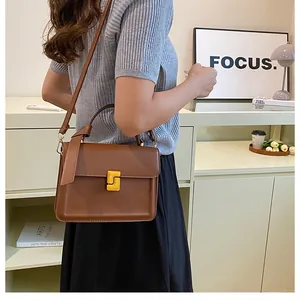 Close-up of vintage brown leather handbag with unique gold square clasp and side tassel detail