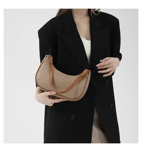 Detail of beige woven hobo bag with brown leather straps styled on a black blazer