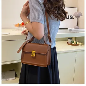 Close-up of a brown leather square crossbody bag with elegant gold clasp and handle