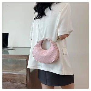 Détail du sac demi-lune rose matelassé avec chaîne en métal porté par un mannequin