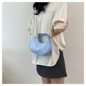 Détail du sac demi-lune bleu clair en cuir matelassé avec une chaîne argentée