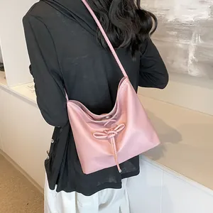 Pink ballet style drawstring shoulder bag with bow detail in soft pearl texture leather