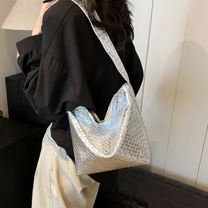 Silberne geflochtene Tragetasche mit Metallic-Finish, getragen als stilvolle Schultertasche