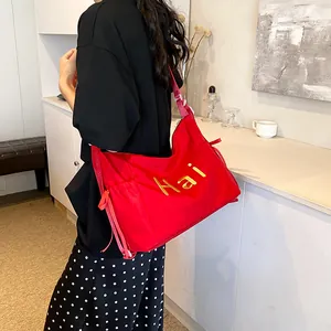 Large bright red canvas tote bag with yellow Hai embroidery and striped shoulder strap