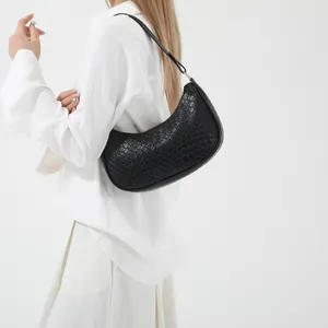Fashionable black crescent shoulder bag with crocodile pattern texture on a model