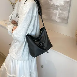 Chic black ballet-style bucket bag with crisscross ribbon design and matte finish