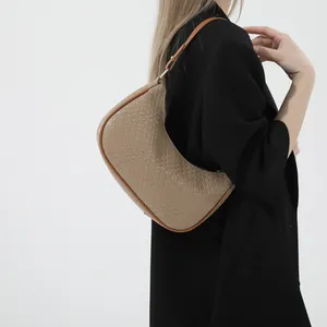 Chic beige woven crescent hobo bag with brown leather trim shown on model shoulder