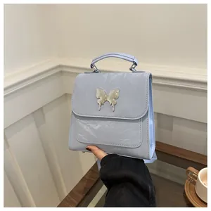 Detail of light blue wrinkled shiny handbag with metallic butterfly on white background