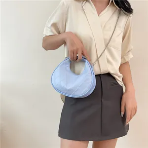 Sac hobo bleu clair matelassé avec chaîne argentée et poignée porté par un mannequin