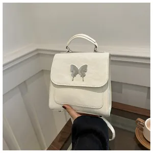 Close-up of cream textured leather handbag with silver butterfly metal buckle detail