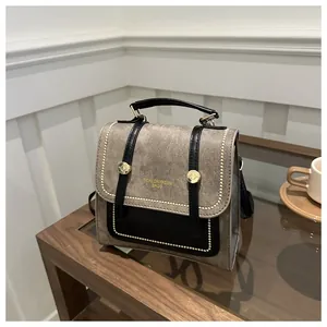 Détail du sac en toile et cuir avec marquage doré sur un décor en bois chaleureux