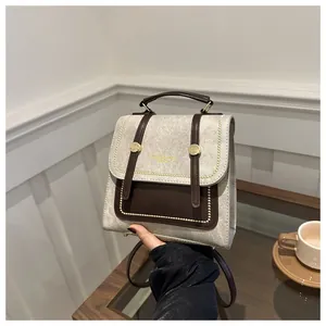 Détail du sac à dos rétro en tissu avec garniture en cuir brun et poignées dorées chic