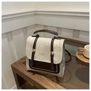 Détail des coutures en toile vintage et de la poignée en cuir d'un sac bandoulière beige