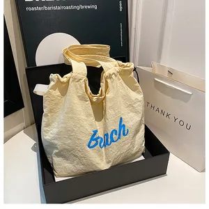 Close-up of yellow wrinkled canvas tote bag with blue Beach text in black display box