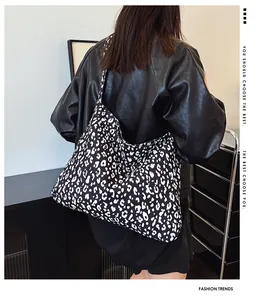 Detail of large black and white leopard print canvas tote bag worn with leather jacket