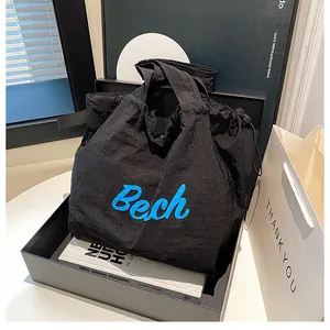 Detail of black canvas tote bag with blue 'Bech' text and drawstring texture detail