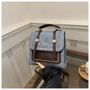 Détail d'un sac rétro gris-bleu avec poignées en cuir marron et accents en métal doré