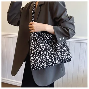 Detailed shoulder view of a large leopard print canvas tote bag on a model