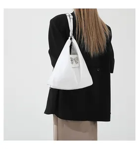 Detailed view of a white triangular PU leather shoulder bag with a silver bow ornament
