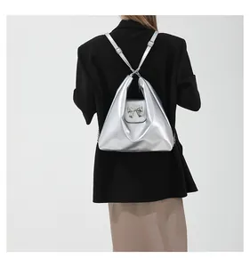 Silver metallic crossbody bag featuring a decorative metal bow and adjustable shoulder strap