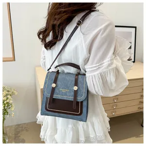 Détail du sac bandoulière vintage en denim et cuir marron avec des accents de rivets dorés