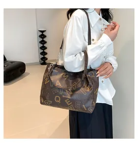 Close-up of large brown tote bag with letter prints and long shoulder strap details