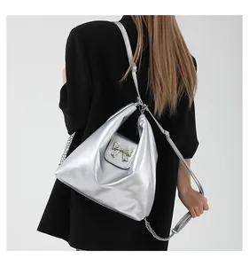 Silver metallic leather shoulder bag with bow detail worn over a black blazer