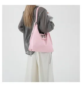 Pink soft PU shoulder bag with silver bow detail worn by model in minimalist studio