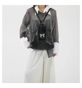 Detail of black PU leather triangle bag with silver bow hardware and metal chain strap