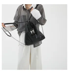 Detail of black soft leather hobo bag with silver metal bow and chain strap on model