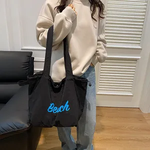 Minimalist black canvas tote bag with blue Beach lettering for casual commuting use