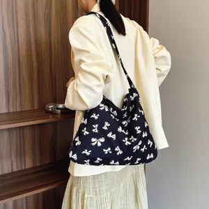 Black canvas tote bag with white bow pattern print and wide shoulder strap