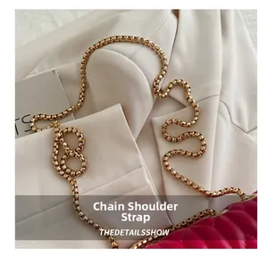 Close-up of golden metal chain strap on magenta quilted leather square shoulder bag