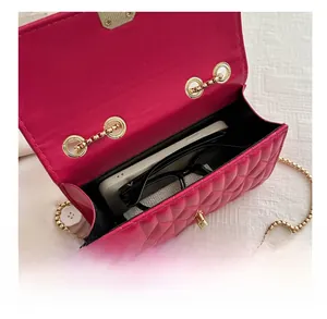 Detail view of fuchsia quilted chain bag showing interior storage for phone and glasses