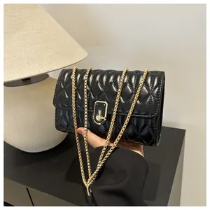 Close-up of black quilted shoulder bag with gold chain strap and elegant rectangular lock