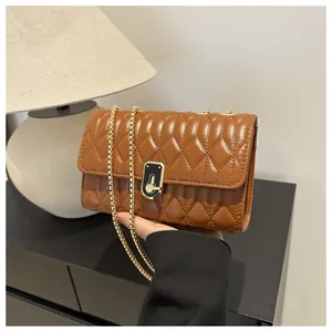 Close-up of caramel quilted chain bag featuring a gold clasp and soft leather texture