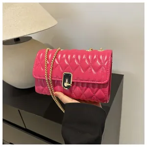 Detail of fuchsia quilted crossbody bag featuring a gold chain strap and metal lock