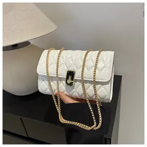 Detail of white quilted leather crossbody bag featuring gold chain strap and turn-lock