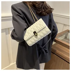 Detailed shot of white quilted shoulder bag with gold chain strap on a model