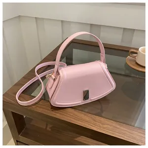 Detailed view of a pink geometric faux leather handbag with silver clasp on a wooden table