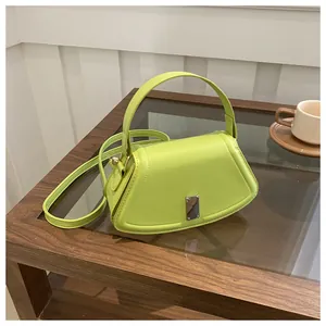 Lime green trapezoidal crossbody bag with a silver metal lock on a wooden desk