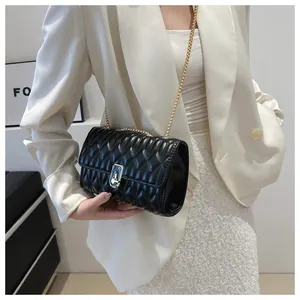 Close-up of black quilted small square bag with gold chain strap and metal lock detail