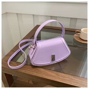 Close-up of light purple handbag with silver buckle and leather strap on wooden table